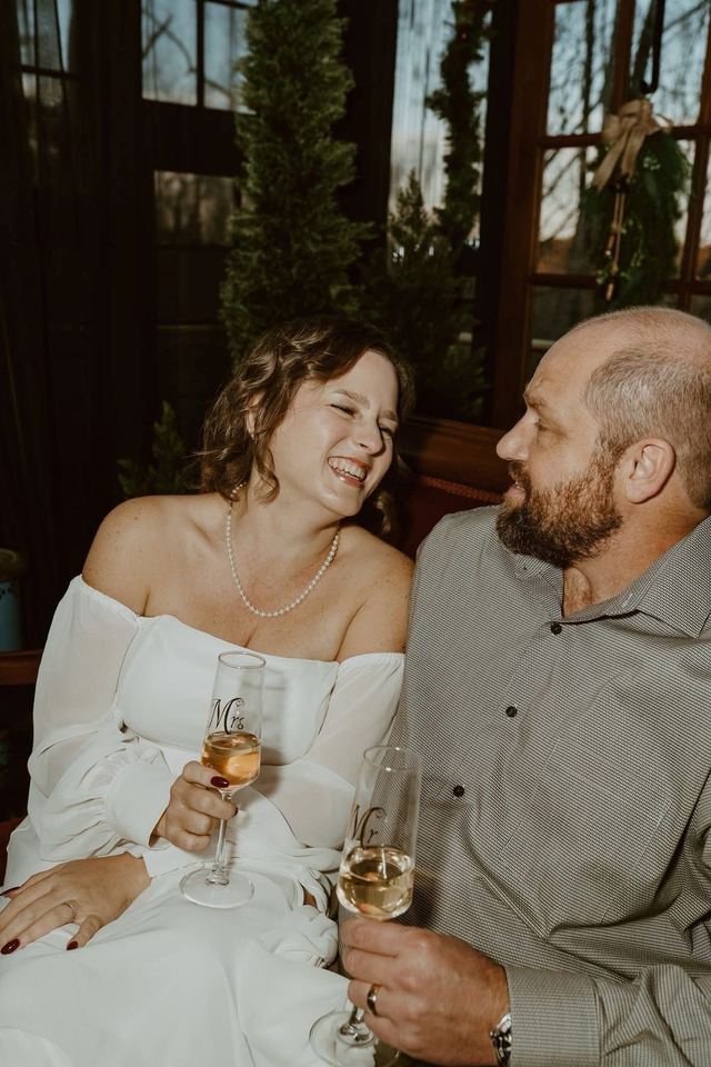 A couple laughing with champagne flutes inside The Glasshouse