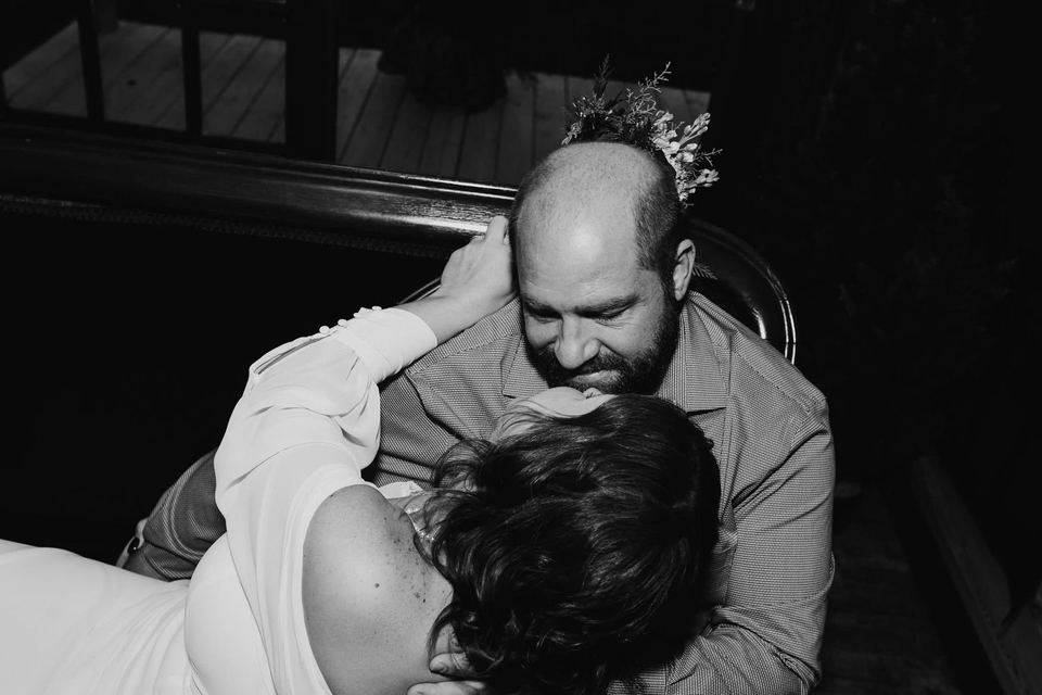 Black-and-white photo of a bride leaning into the groom’s embrace