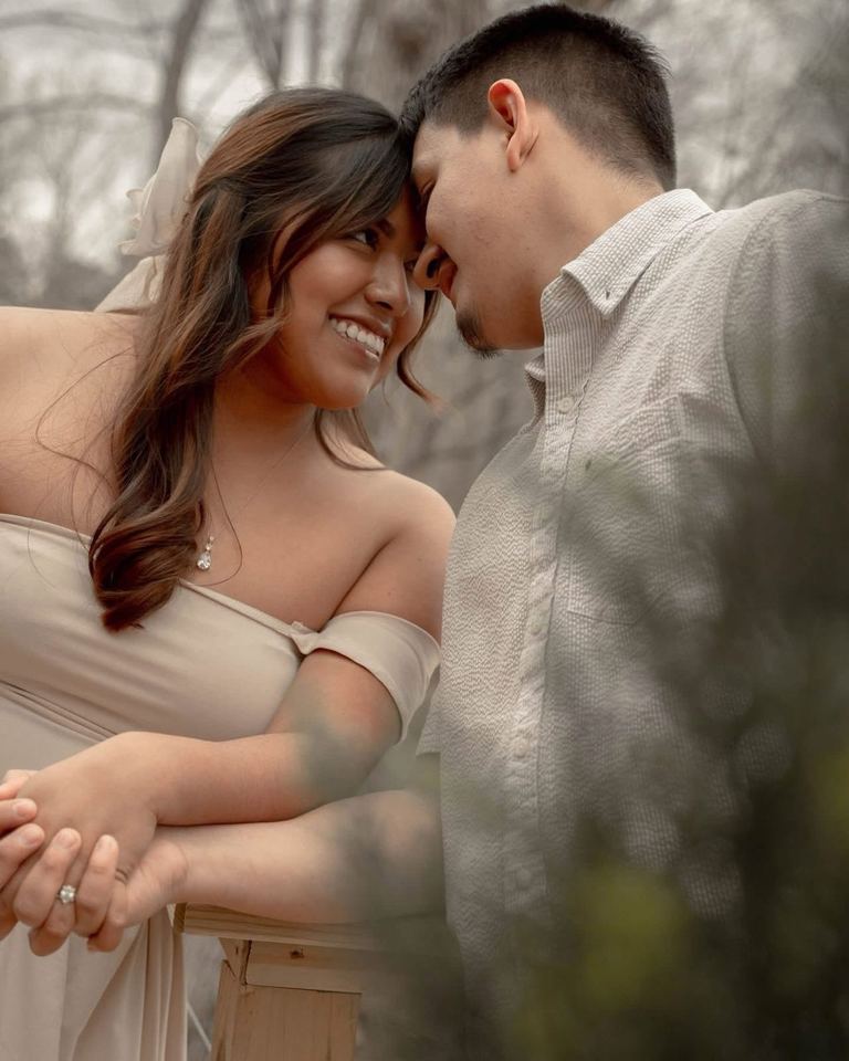 A couple resting forehead to forehead at a wooden railing