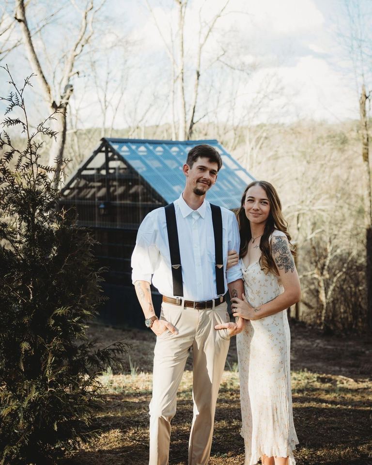 A couple standing together in front of The Glasshouse in spring
